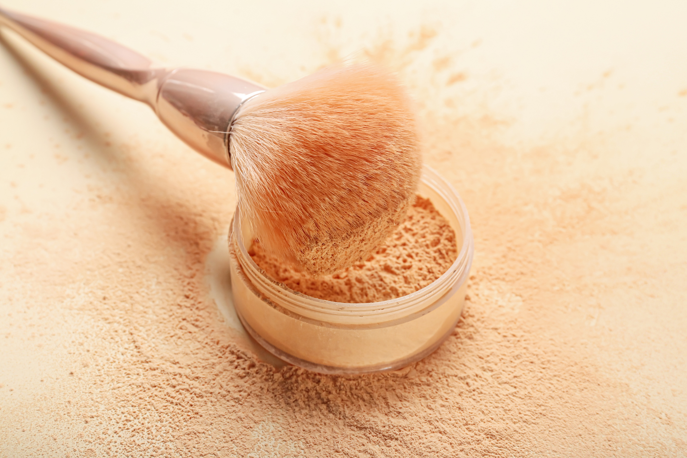 Makeup Brush and Loose Powder on Light Background